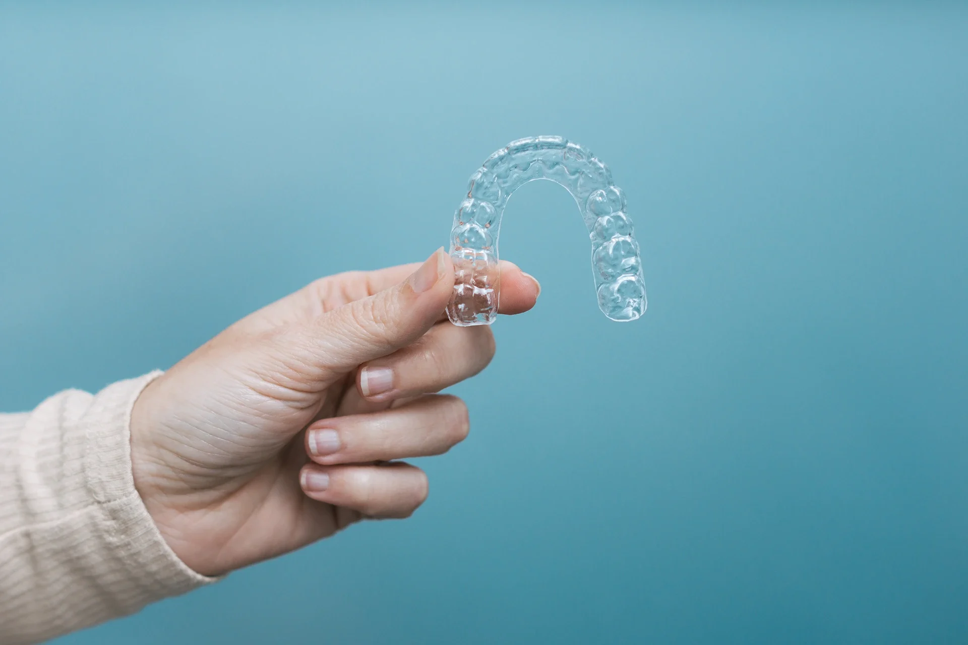 Skaidri kapa laikoma rankoje – dantų tiesinimo kapomis priemonė, naudojama estetinei ortodontijai be breketų